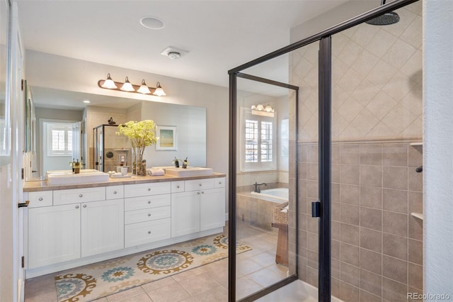 full bathroom featuring double vanity, a bath, tile patterned flooring, a shower stall, and a sink