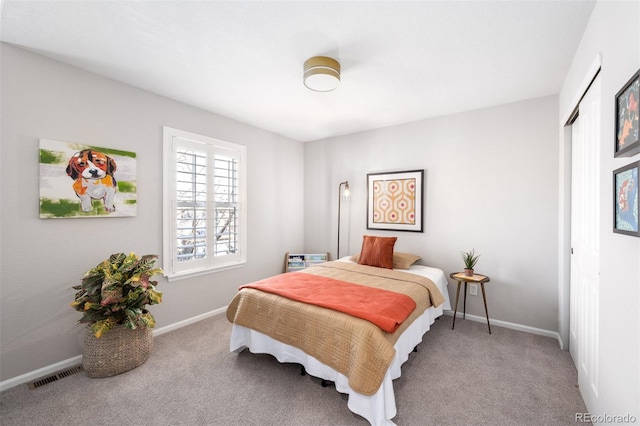 carpeted bedroom with a closet, visible vents, and baseboards