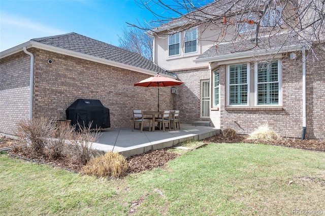 back of property with a patio, a shingled roof, a lawn, and brick siding