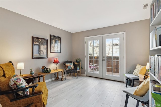 sitting room featuring light wood finished floors, baseboards, visible vents, and french doors