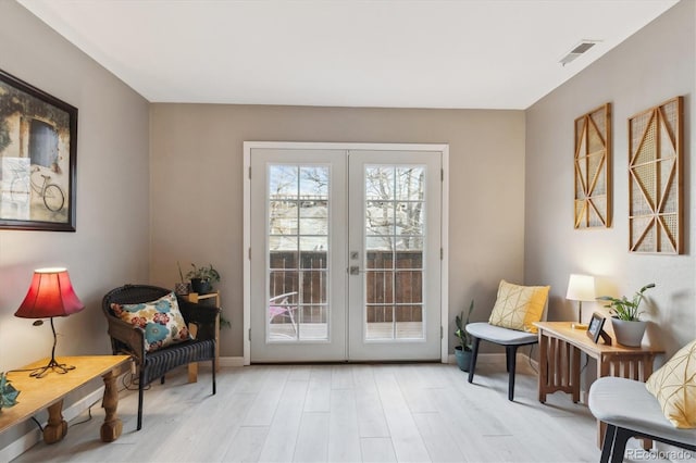 living area featuring french doors, visible vents, and light wood-style floors