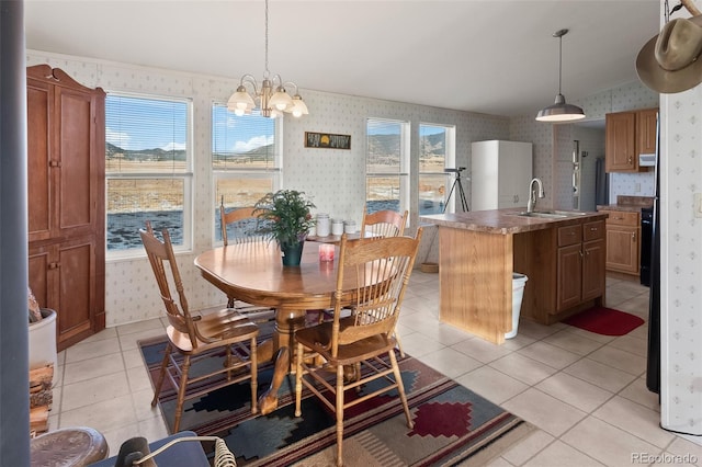 dining space with sink, plenty of natural light, light tile patterned flooring, and an inviting chandelier