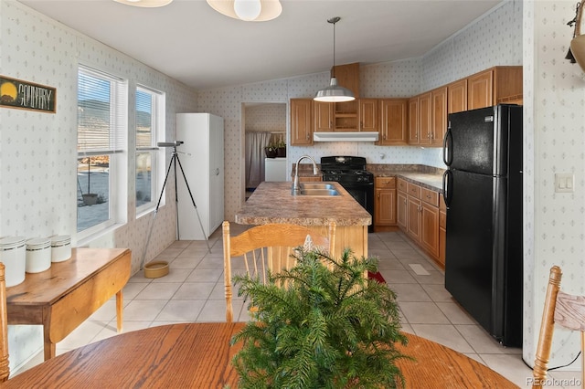 kitchen with vaulted ceiling, sink, black appliances, light tile patterned floors, and hanging light fixtures