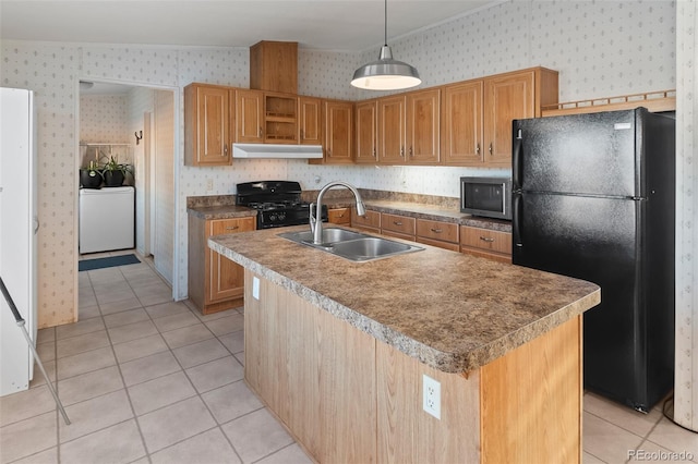 kitchen featuring decorative light fixtures, sink, an island with sink, and black appliances