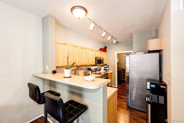 452 Black Feather Loop Unit 608, Castle Rock, CO 80104 - kitchen with appliances with stainless steel finishes, light brown cabinets, light countertops, dark wood-style floors, and a peninsula