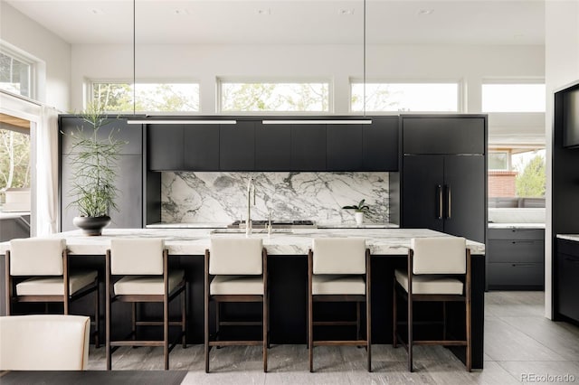 140 S Glencoe St, Denver, CO 80246 - kitchen with dark cabinetry, decorative backsplash, modern cabinets, a kitchen bar, and an island with sink