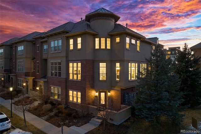 view of front facade featuring metal roof, brick siding, a standing seam roof, and stucco siding