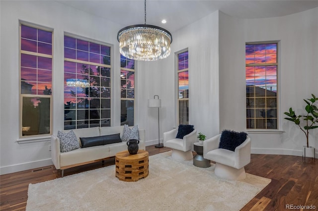 living area with an inviting chandelier, baseboards, and wood finished floors