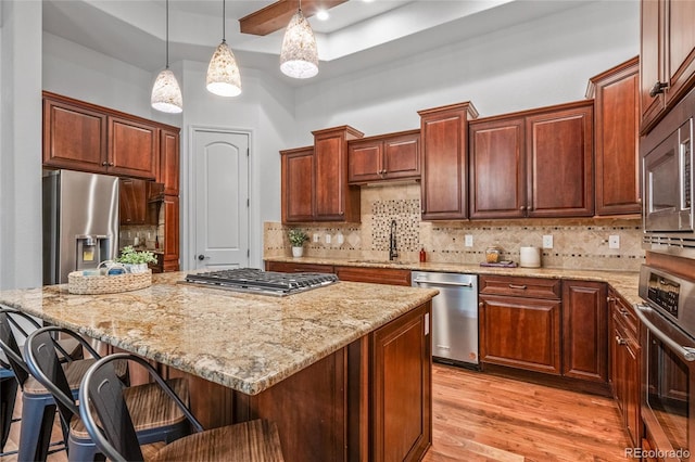 kitchen featuring a center island, a breakfast bar area, stainless steel appliances, light wood-style floors, and a sink