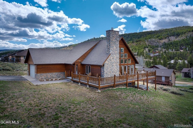 62 897, Grand Lake, CO 80447 - back of house with stone siding, an attached garage, a yard, a deck, and a chimney