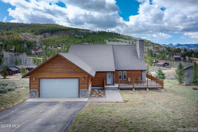 62 897, Grand Lake, CO 80447 - rustic home with a garage, driveway, stone siding, a wooded view, and a chimney