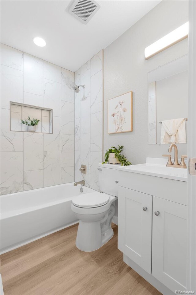 bathroom with shower / bathtub combination, toilet, wood finished floors, vanity, and visible vents