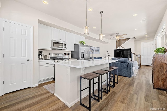 kitchen featuring white cabinetry, appliances with stainless steel finishes, a kitchen island with sink, and a kitchen breakfast bar