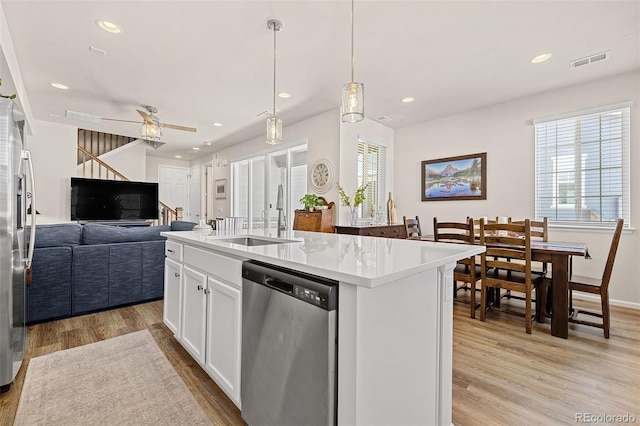 kitchen with sink, hanging light fixtures, white cabinets, a center island with sink, and stainless steel dishwasher