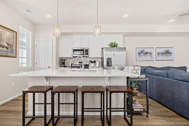 kitchen with pendant lighting, a center island with sink, a breakfast bar area, and appliances with stainless steel finishes