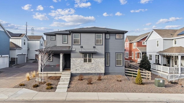 view of front facade with driveway, stone siding, a residential view, fence, and cooling unit