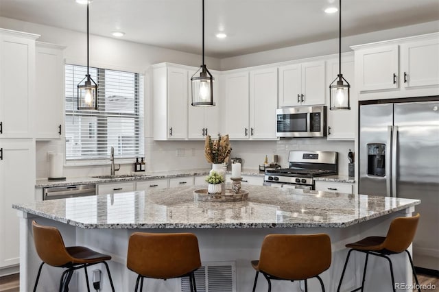 kitchen with a center island, stainless steel appliances, tasteful backsplash, white cabinets, and a sink