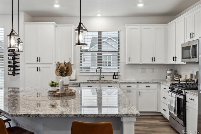 kitchen featuring white cabinetry, appliances with stainless steel finishes, a kitchen breakfast bar, and a sink