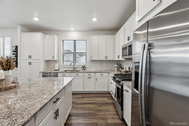 kitchen with dark wood-style floors, appliances with stainless steel finishes, white cabinetry, a sink, and recessed lighting