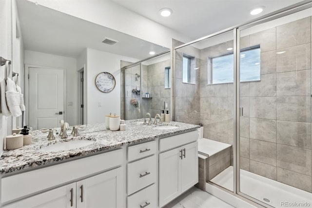 bathroom featuring double vanity, a stall shower, visible vents, and a sink