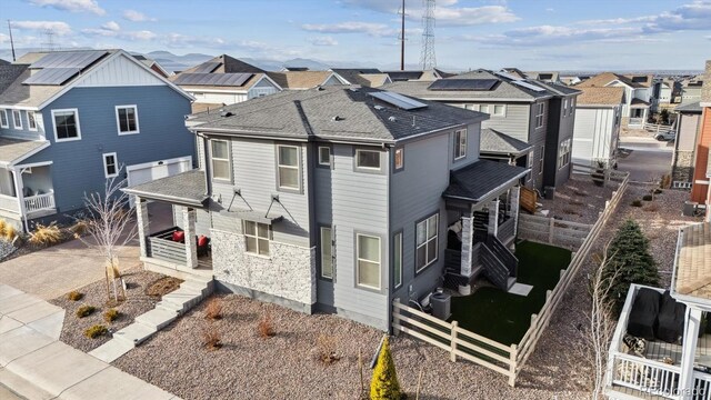 view of front of home with central air condition unit, a shingled roof, a residential view, and fence