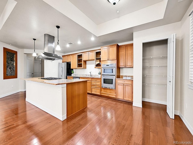 kitchen featuring hardwood / wood-style flooring, a kitchen island, appliances with stainless steel finishes, and island range hood