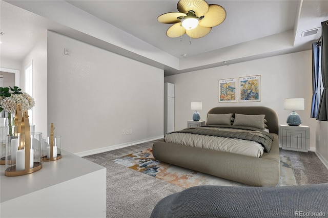 carpeted bedroom with a tray ceiling, visible vents, baseboards, and ceiling fan