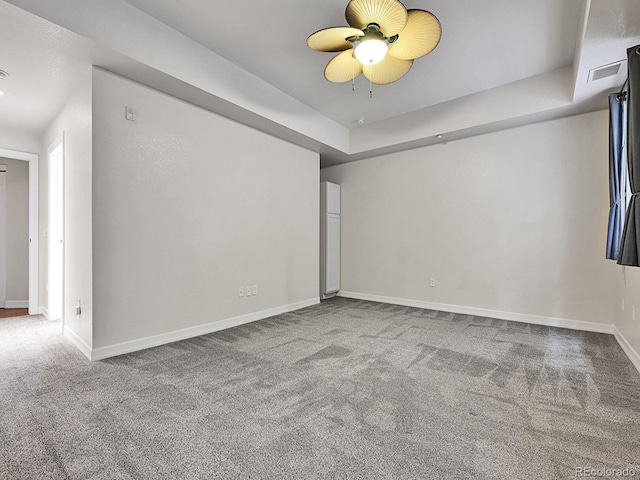 empty room featuring visible vents, ceiling fan, baseboards, carpet, and a tray ceiling