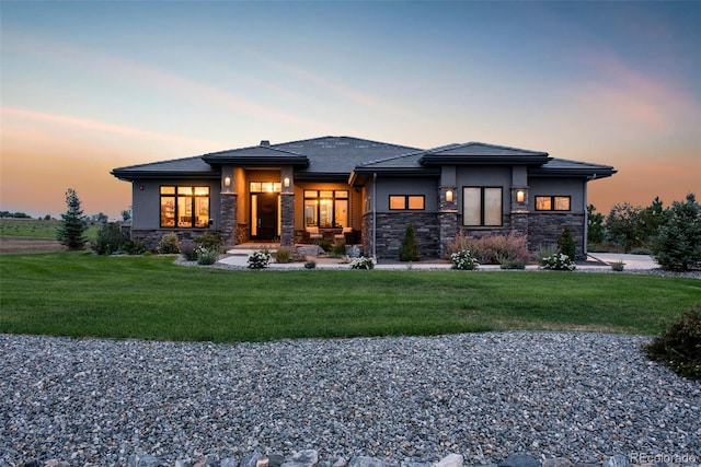 back of house featuring stone siding, a yard, and stucco siding