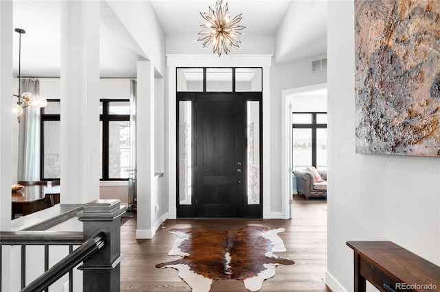 entryway featuring an inviting chandelier, visible vents, a wealth of natural light, and dark wood-style flooring