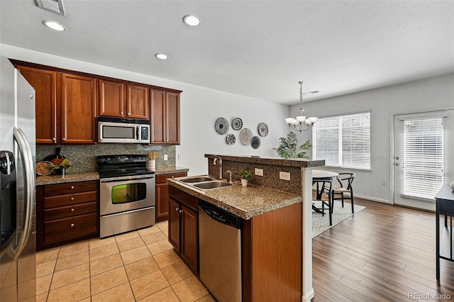 13020 Grant Cir W Unit A, Thornton, CO 80241 - kitchen featuring stainless steel appliances, a sink, backsplash, a chandelier, and a breakfast bar area