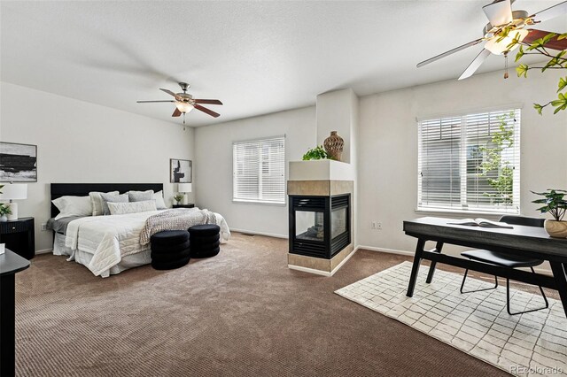 13020 Grant Cir W Unit A, Thornton, CO 80241 - bedroom featuring carpet, a multi sided fireplace, baseboards, and a ceiling fan
