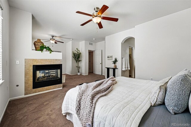 13020 Grant Cir W Unit A, Thornton, CO 80241 - bedroom with carpet floors, a tiled fireplace, arched walkways, baseboards, and a ceiling fan