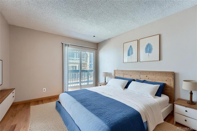 3480 S Eagle St Unit 101, Aurora, CO 80014 - bedroom with light wood-type flooring, access to exterior, and a textured ceiling