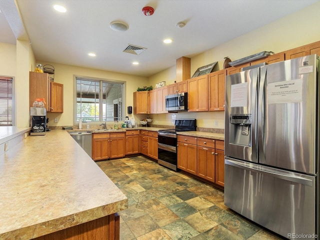 7885 Buckhorn Grn Unit 131, Frederick, CO 80530 - kitchen with appliances with stainless steel finishes, light countertops, recessed lighting, dark stone finish flooring, and brown cabinetry