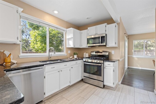 2640 Overlook Dr, Broomfield, CO 80020 - kitchen featuring appliances with stainless steel finishes, white cabinetry, dark stone counters, recessed lighting, and light wood-style floors
