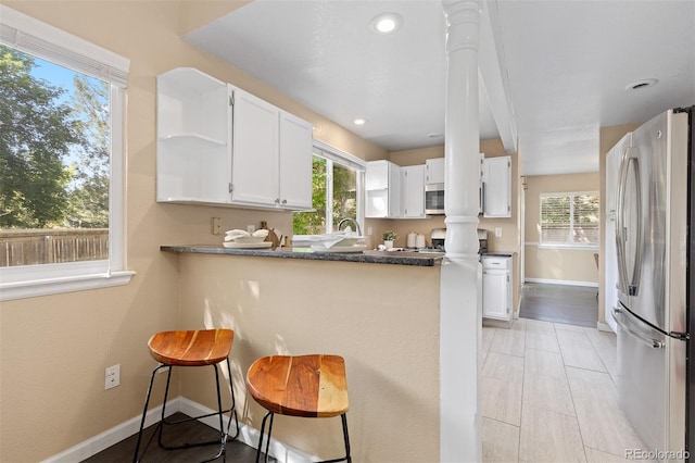 2640 Overlook Dr, Broomfield, CO 80020 - kitchen featuring appliances with stainless steel finishes, a peninsula, white cabinets, open shelves, and a kitchen breakfast bar