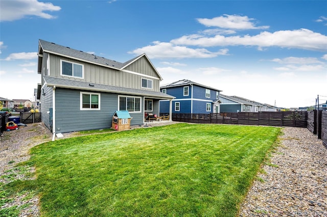 rear view of house with board and batten siding, a fenced backyard, a lawn, and a patio