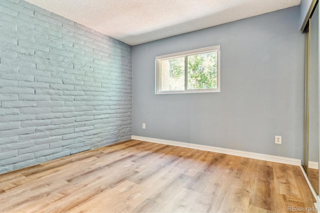 1060 S Parker Rd Unit 25, Denver, CO 80231 - unfurnished room featuring wood finished floors, a textured ceiling, and brick wall
