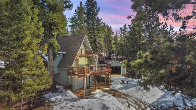 exterior space with roof with shingles and a deck