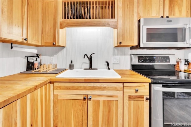 kitchen with stainless steel appliances, wood counters, and a sink