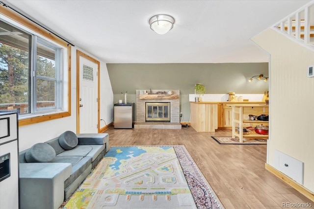 living area featuring baseboards, light wood finished floors, and a glass covered fireplace