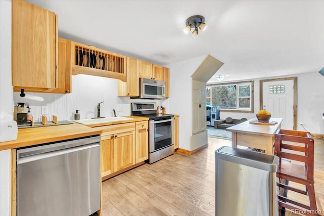 kitchen with stainless steel appliances, light countertops, a sink, and light wood-type flooring