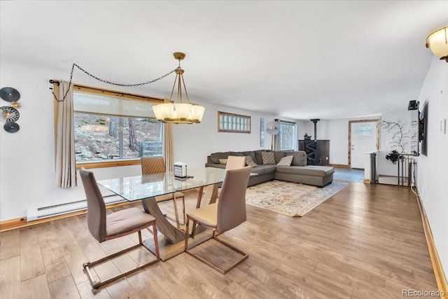 dining room with light wood-style flooring, baseboards, baseboard heating, and plenty of natural light