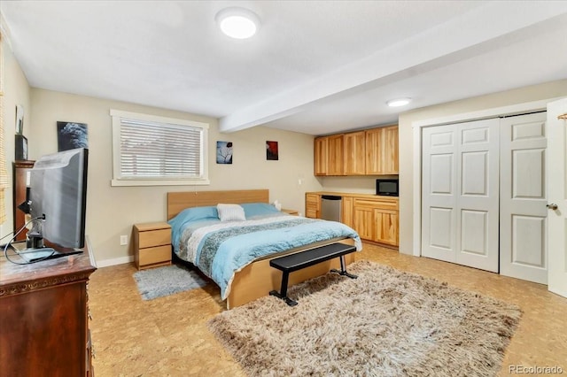 bedroom featuring built in desk, baseboards, refrigerator, a closet, and beamed ceiling