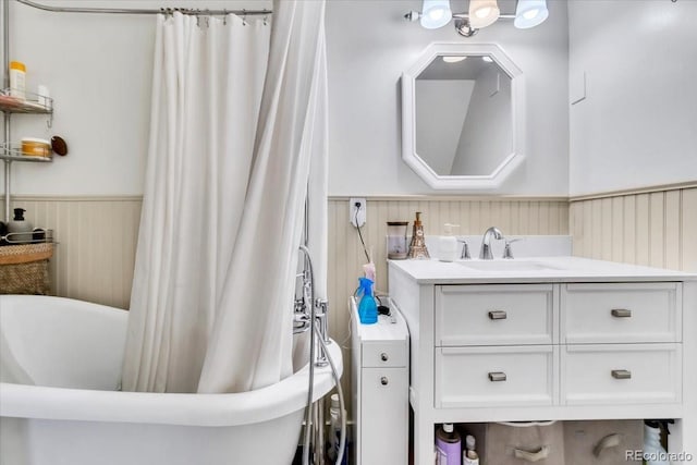 full bath with a wainscoted wall, vanity, and a freestanding bath