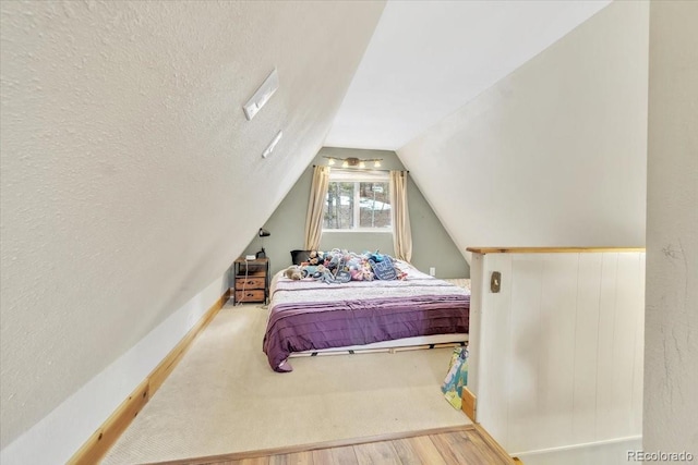 bedroom featuring vaulted ceiling, a textured ceiling, and wood finished floors