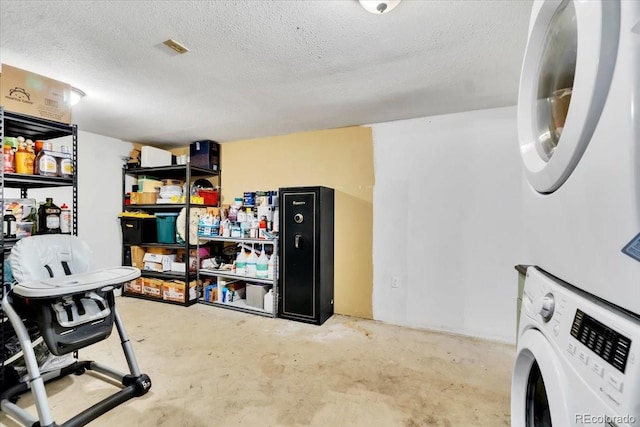 interior space featuring a textured ceiling, stacked washer and dryer, and laundry area