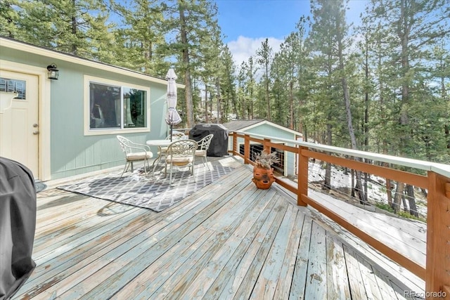 wooden deck with outdoor dining space and a grill