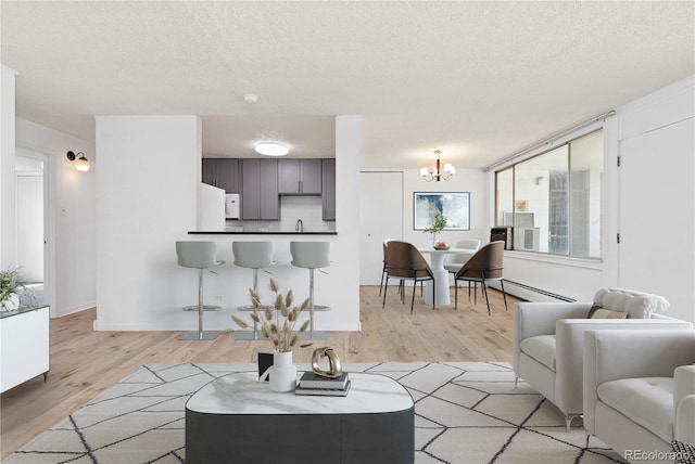 10185 W 25th Ave Unit 33, Lakewood, CO 80215 - living area featuring light wood-type flooring, baseboard heating, a chandelier, and a textured ceiling